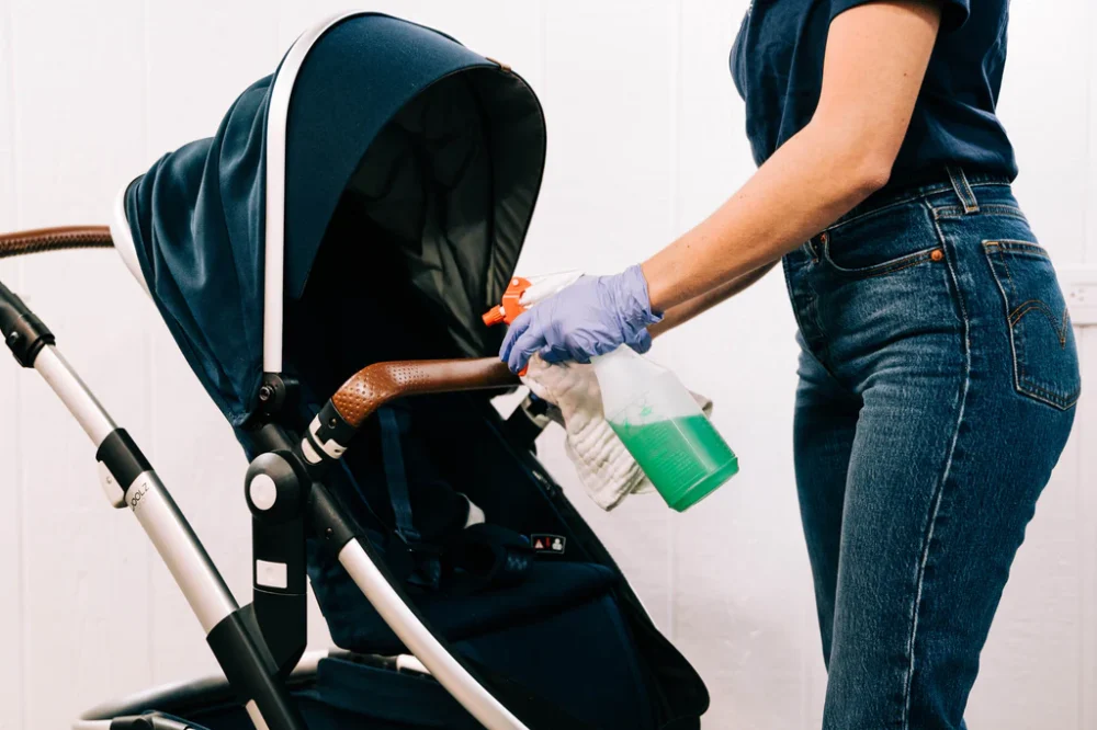 woman holding spray bottle to clean stroller